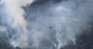 helicopter dropping water on wildfire depicting urgency for preparing for the fire season